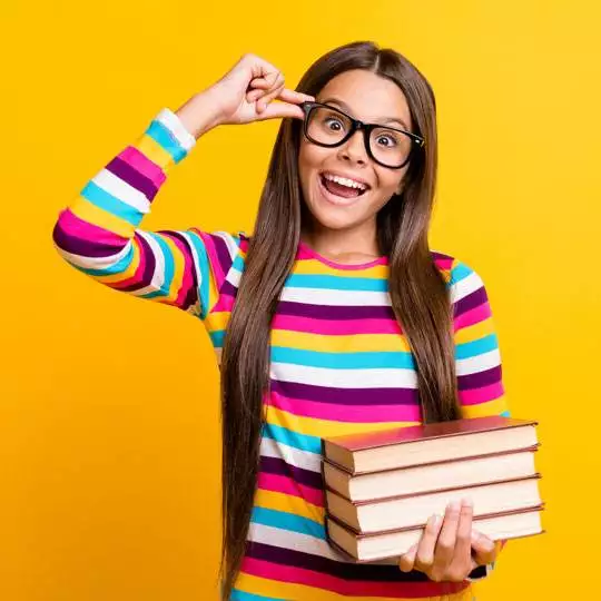 Teen holding a stack of books and smiling
