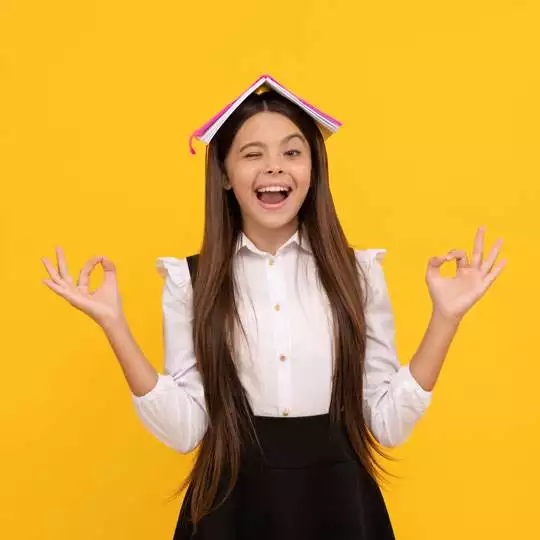 Teen smiling with a book on their head