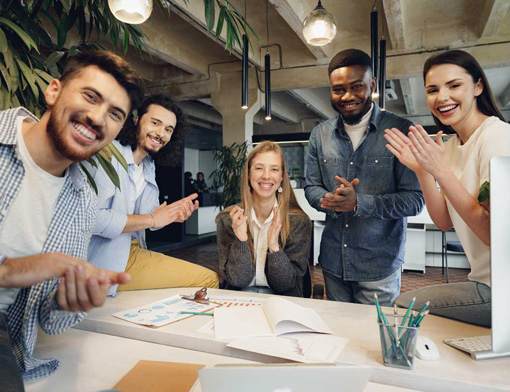 Group of co-workers clapping and cheering around desk.